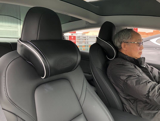 Man sitting inside a Tesla with the black EV Premium Tesla headrests installed