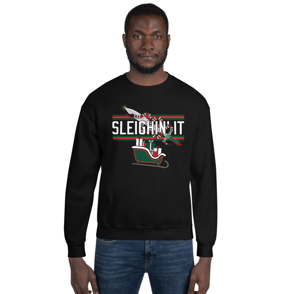 Man wearing a black Christmas-themed sweatshirt with the text "SLEIGHIN' IT" on it