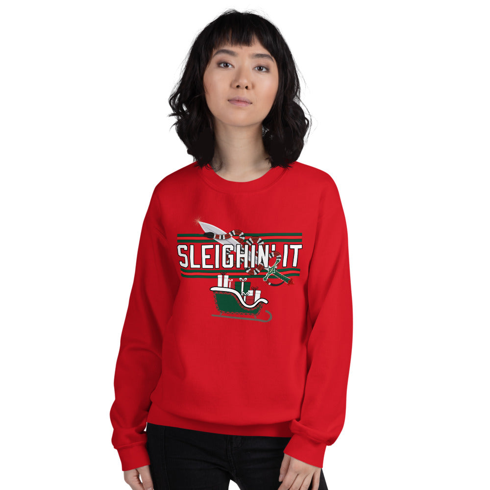 Woman wearing a red Christmas-themed sweatshirt with the text "SLEIGHIN' IT" on it